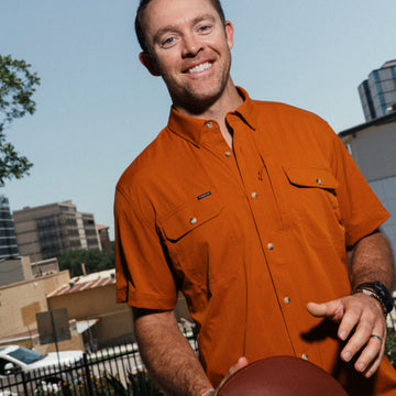 Colt McCoy holding a football while wearing the smokey shirt