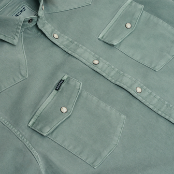 Close-up of a green button-up shirt with flap pockets and snap buttons, featuring The Ventura label.