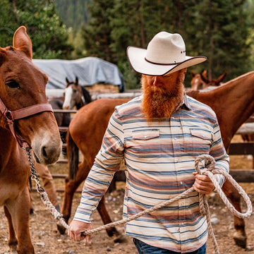 man pulling horse wearing saddle blanket flannel
