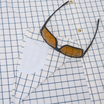 Sunglasses sitting on button down blue shirt