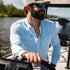 guy driving boat in light blue long sleeve pearl snap shirt