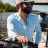 guy driving boat in light blue long sleeve pearl snap shirt