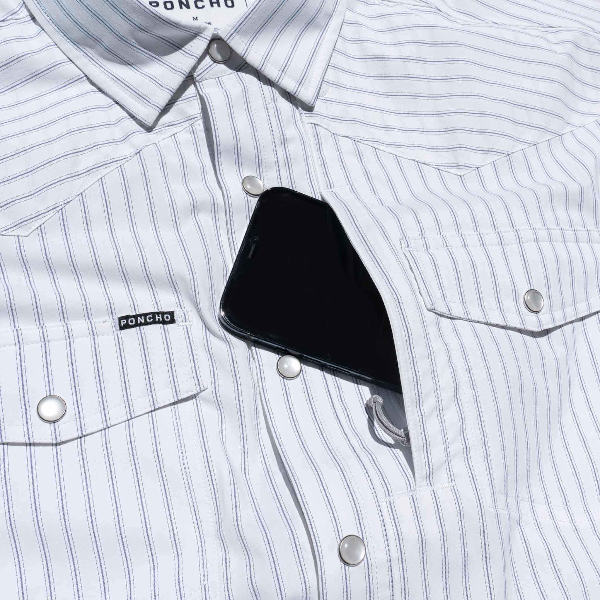 Close up of phone going into the front chest zipper pocket of the striped western shirt