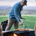 man grilling wearing medium wash blue denim long sleeve pearl snap shirt