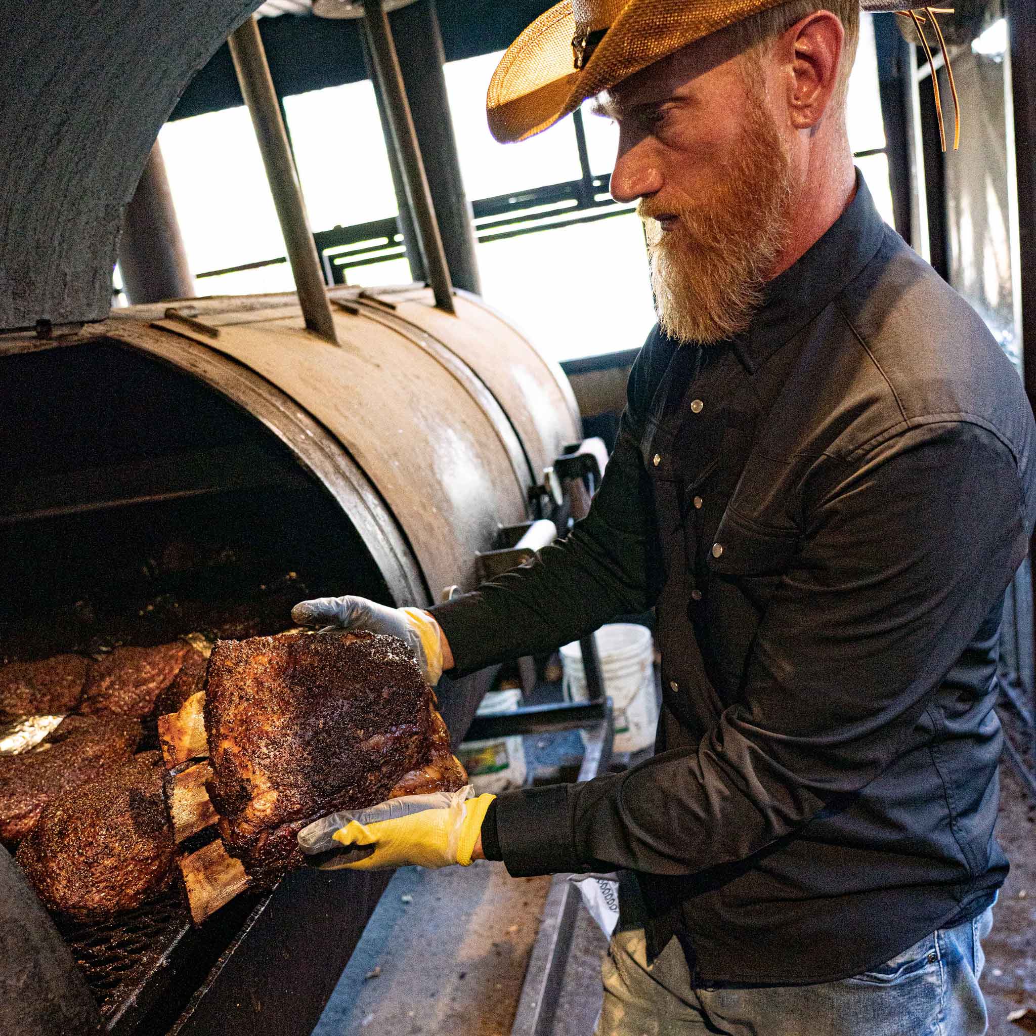 guy showing brisket bbq in black long sleeve pearl snap shirt 