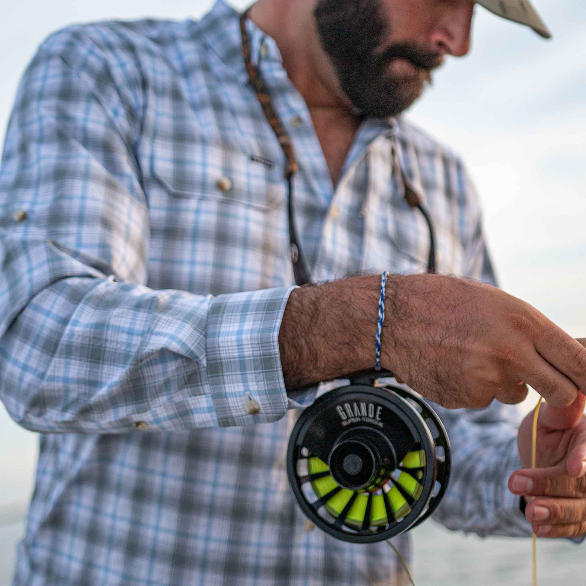 man fishing while wearing grey / blue plaid long sleeve shirt