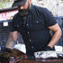Man wearing black short sleeve shirt wrapping brisket