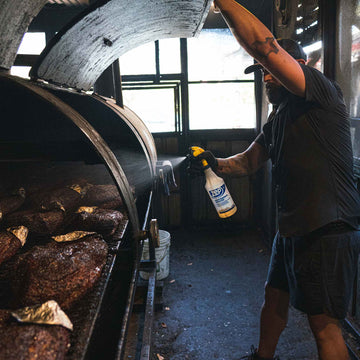 guy spraying briskey in black short sleeve pearl snap shirt