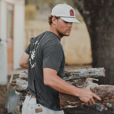 Man wearing Black Agave T-Shirt carrying firewood outdoors in a natural setting
