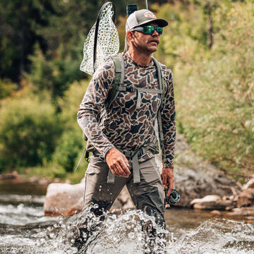 man walking in water wearing camo hoodie