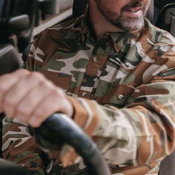 Man wearing long sleeve camo flannel shirt driving