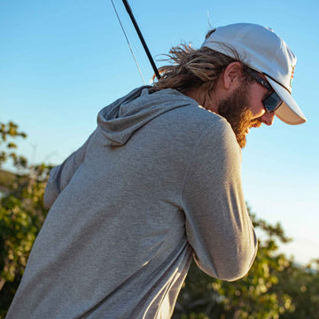 man holding fishing rd wearing grey hoodie
