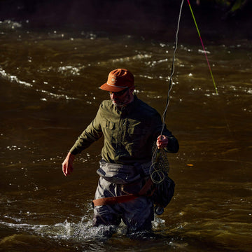 guy walking in river wearing waders