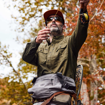 man wearing moss green long sleeve flannel casting fly rod