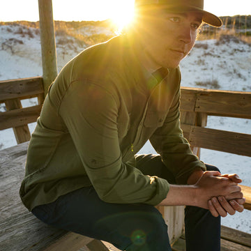 guy wearing moss green flannel sitting on bench