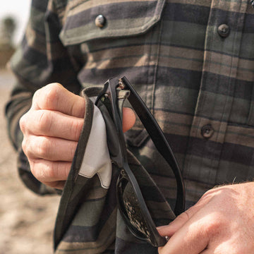 Image of personal cleaning their glasses with the lens cloth on the Kodiak plaid flannel