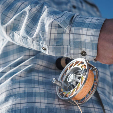 Close up of fishing reel, and sleeve of Blue Bison shirt