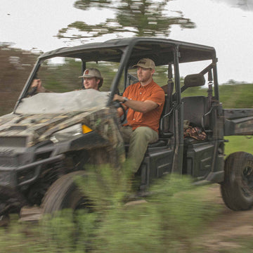 Colt McCoy driving buggy while wearing burnt orange short sleeve pearl snap shirt