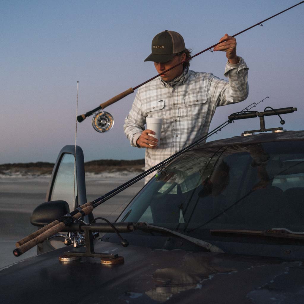 Man on beach in flannel shirt with fishing gear