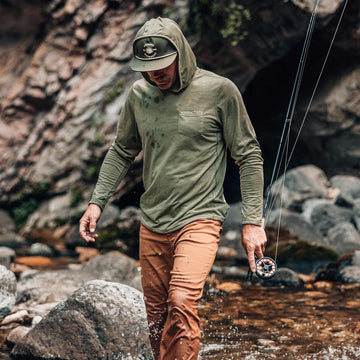 guy walking through water wearing moss green performance hoodie