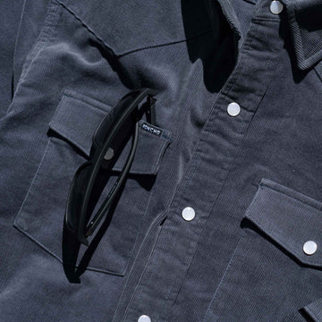 closeup of sunglasses slit on navy corduroy pearl snap shirt