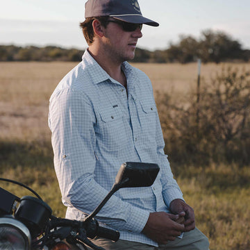 Man sitting on motorcycle wearing plaid long sleeve shirt