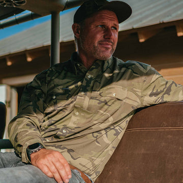 man leaning back wearing long sleeve camo shirt