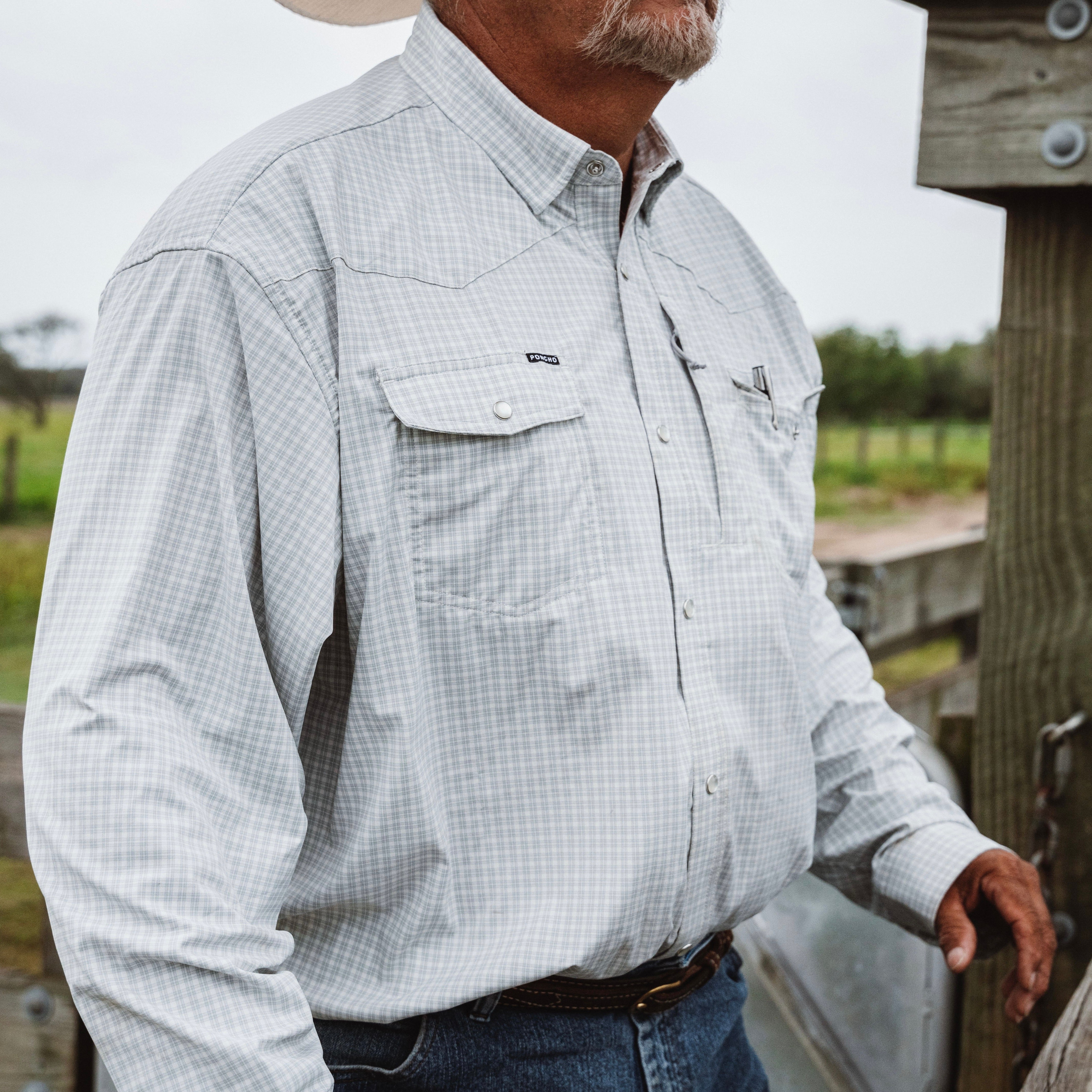 Man stands wearing a checkered button down western shirt