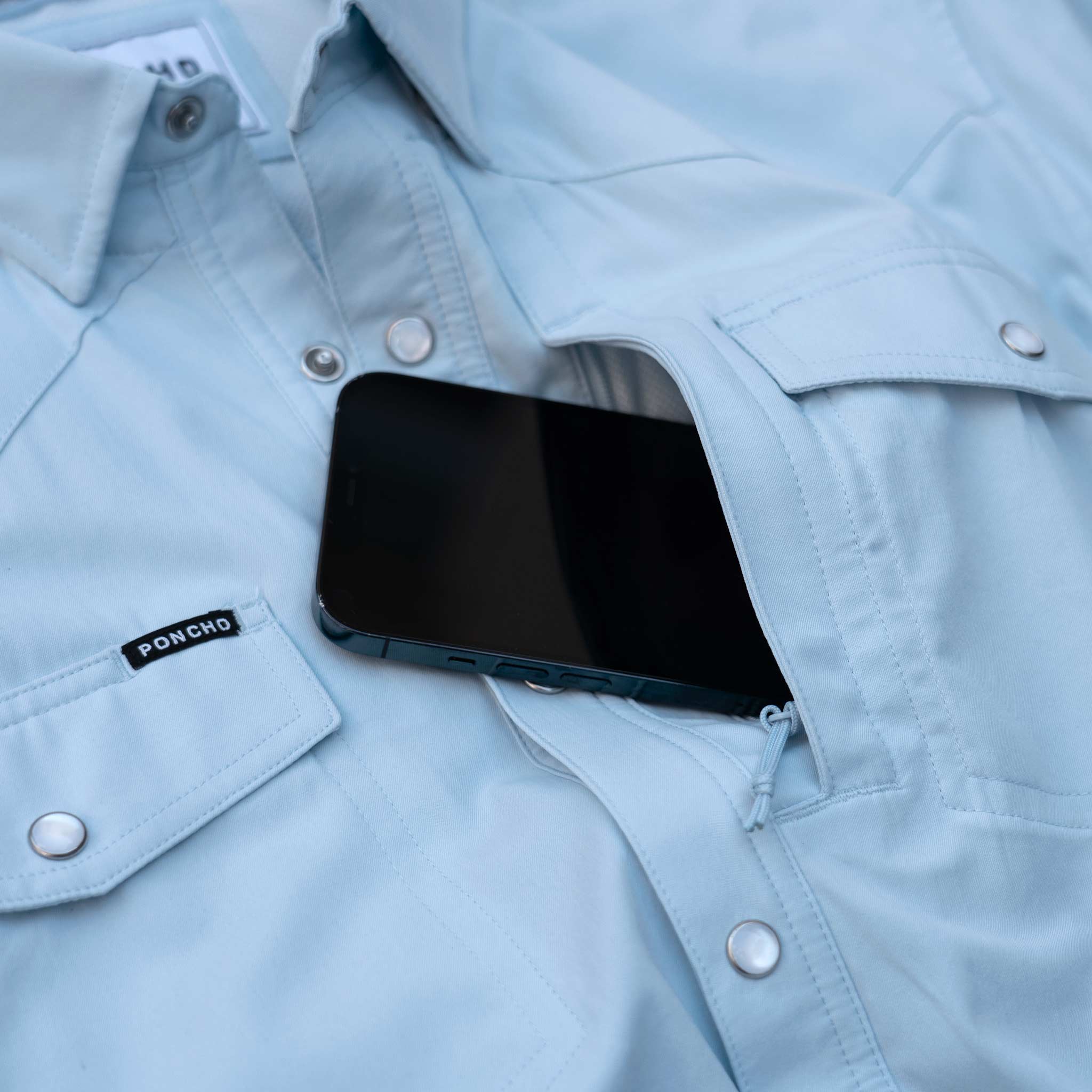 phone in zip pocket in light blue long sleeve pearl snap shirt