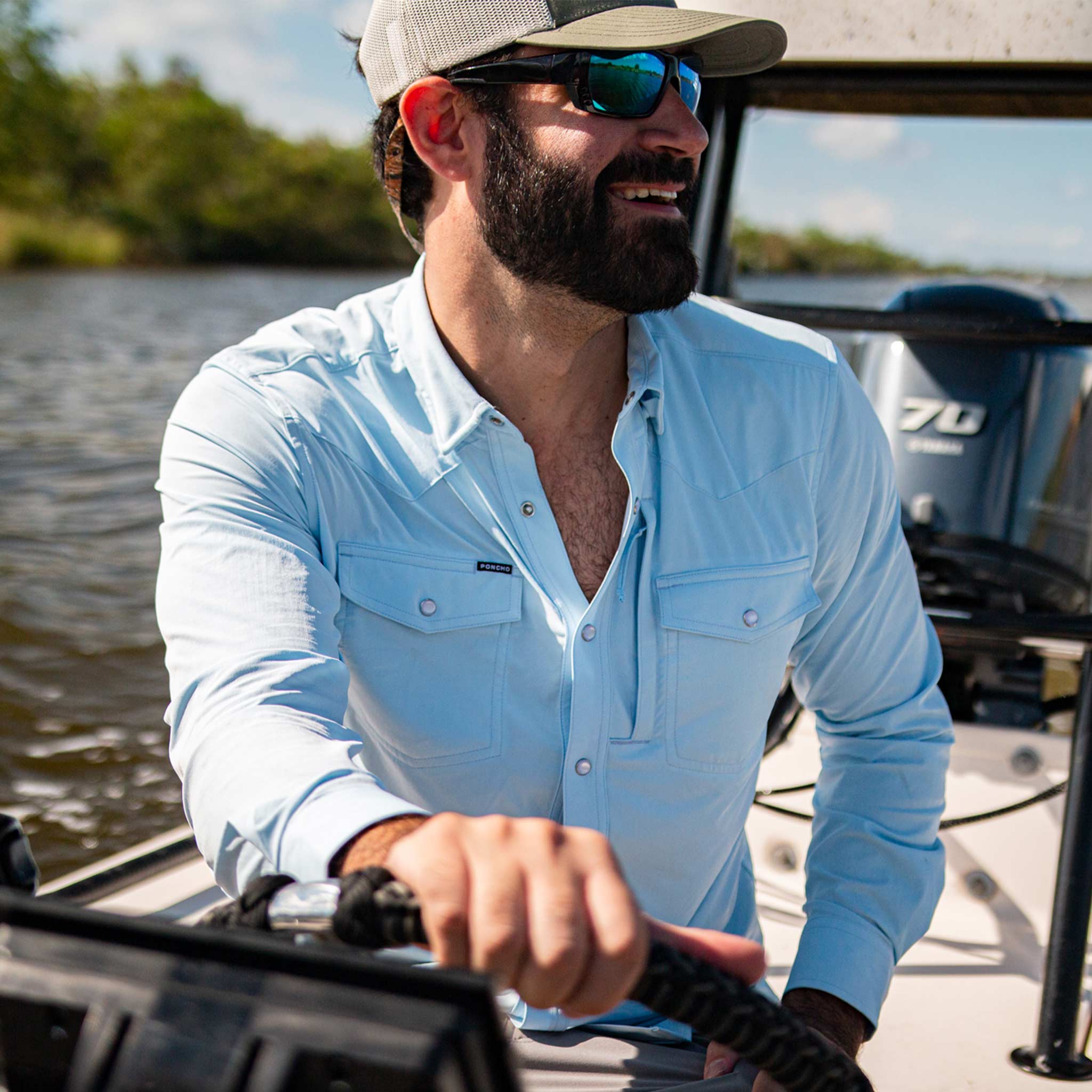 guy driving boat in light blue long sleeve pearl snap shirt