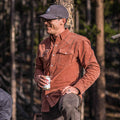 guy wearing shirt standing in woods holding beer