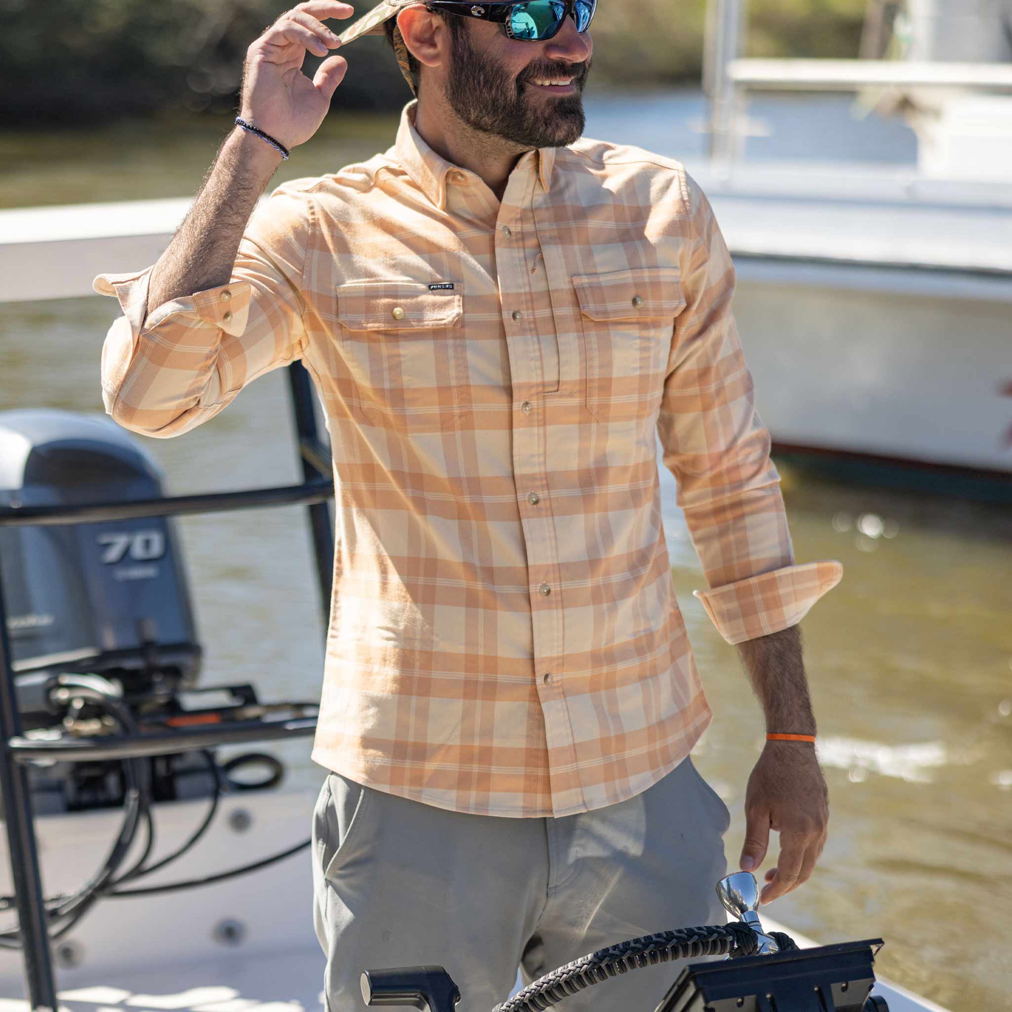 man standing on boat wearing flannel shirt