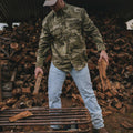 man moves firewood in long sleeve camo shirt