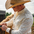 Man holding the reins of a horse in the floral western long sleeve shirt