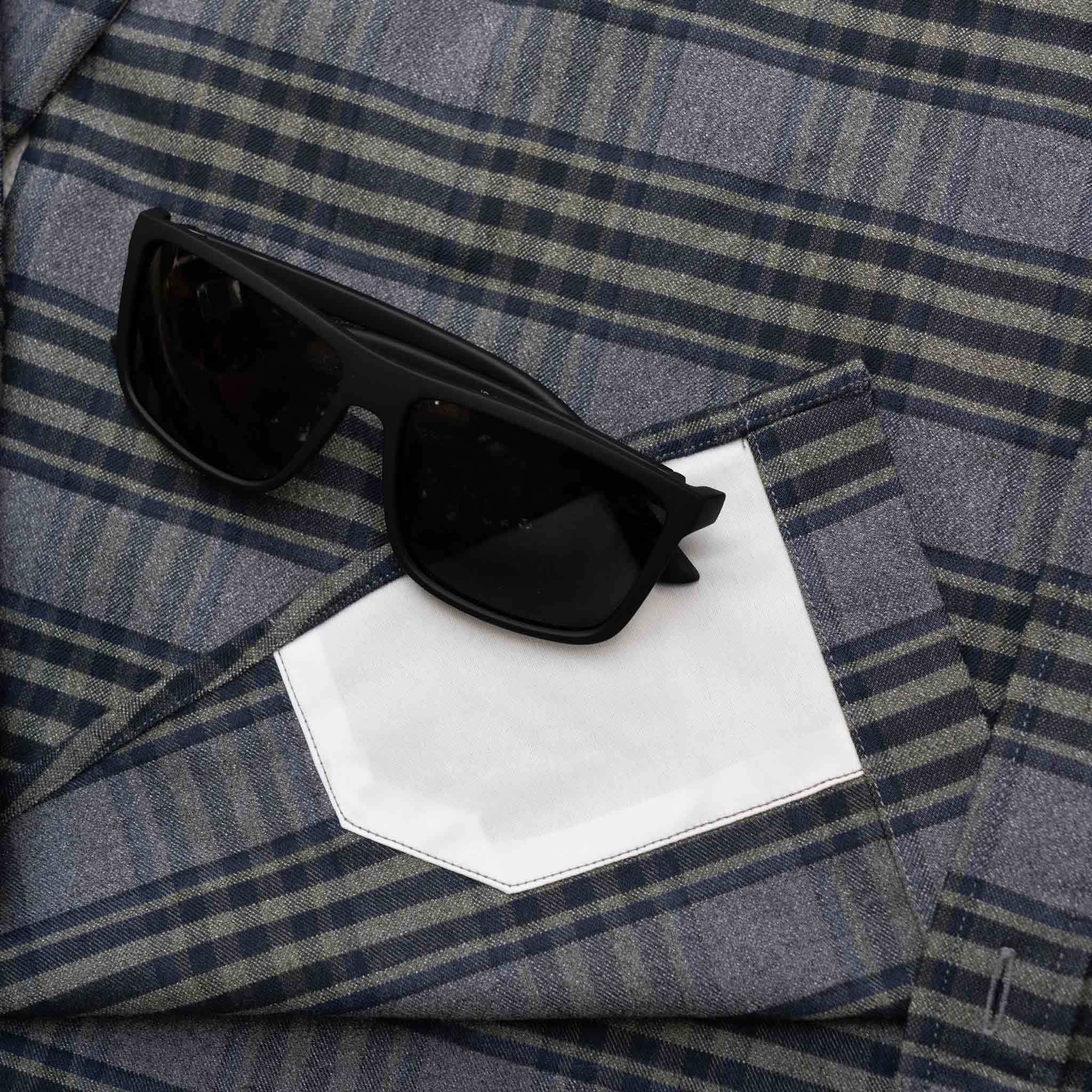Image of sunglasses on top of the lens cloth on the grey and olive plaid flannel