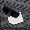Image of sunglasses on top of the lens cloth on the grey and olive plaid flannel