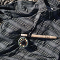 Image of a fishing rod on top of a grey and olive plaid flannel