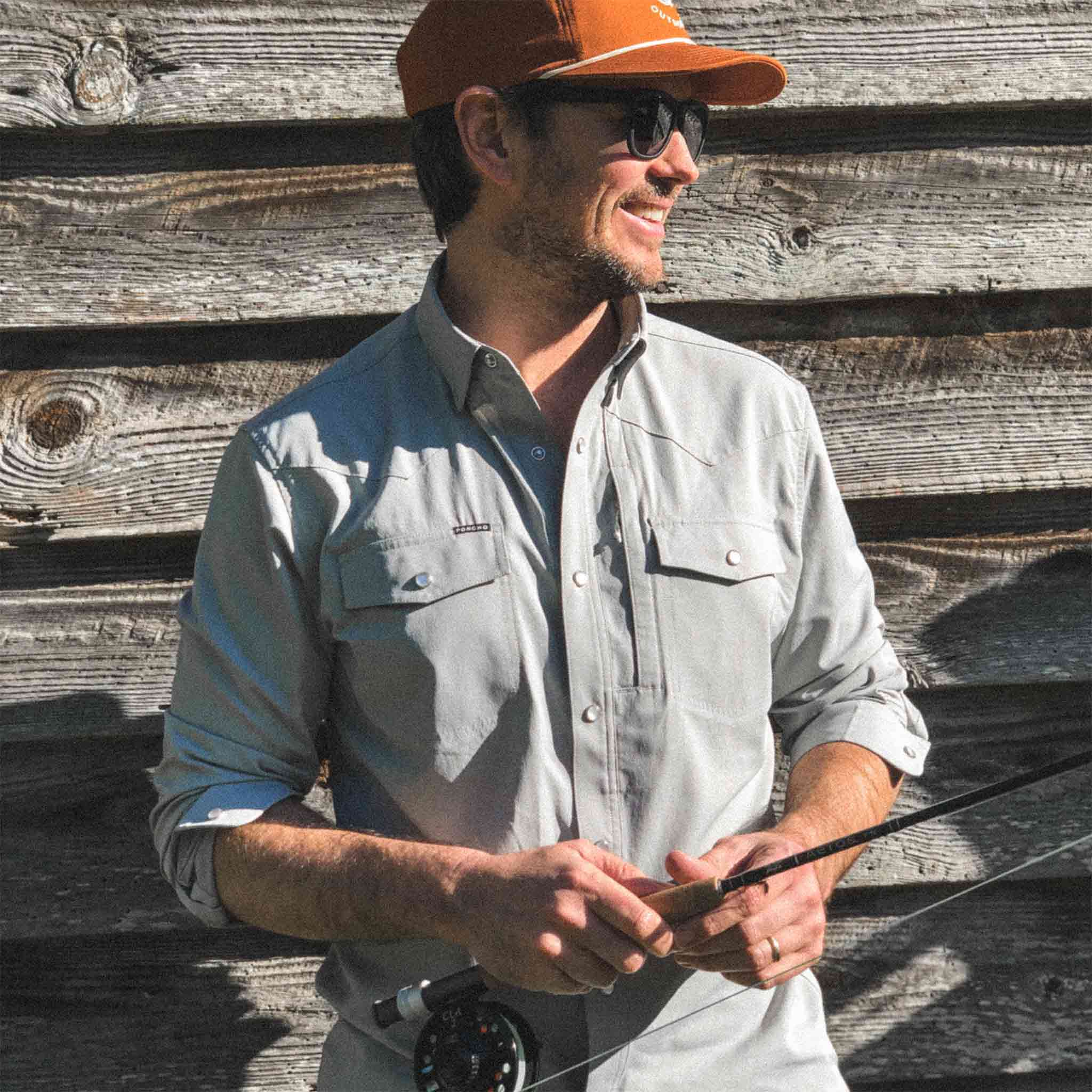 Man in San Saba shirt with Orange Hat smiling holding fishing rod