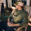 guy in moss green in chair on porch