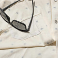 Closeup of floral shirt with sunglasses and sunglasses cleaner.