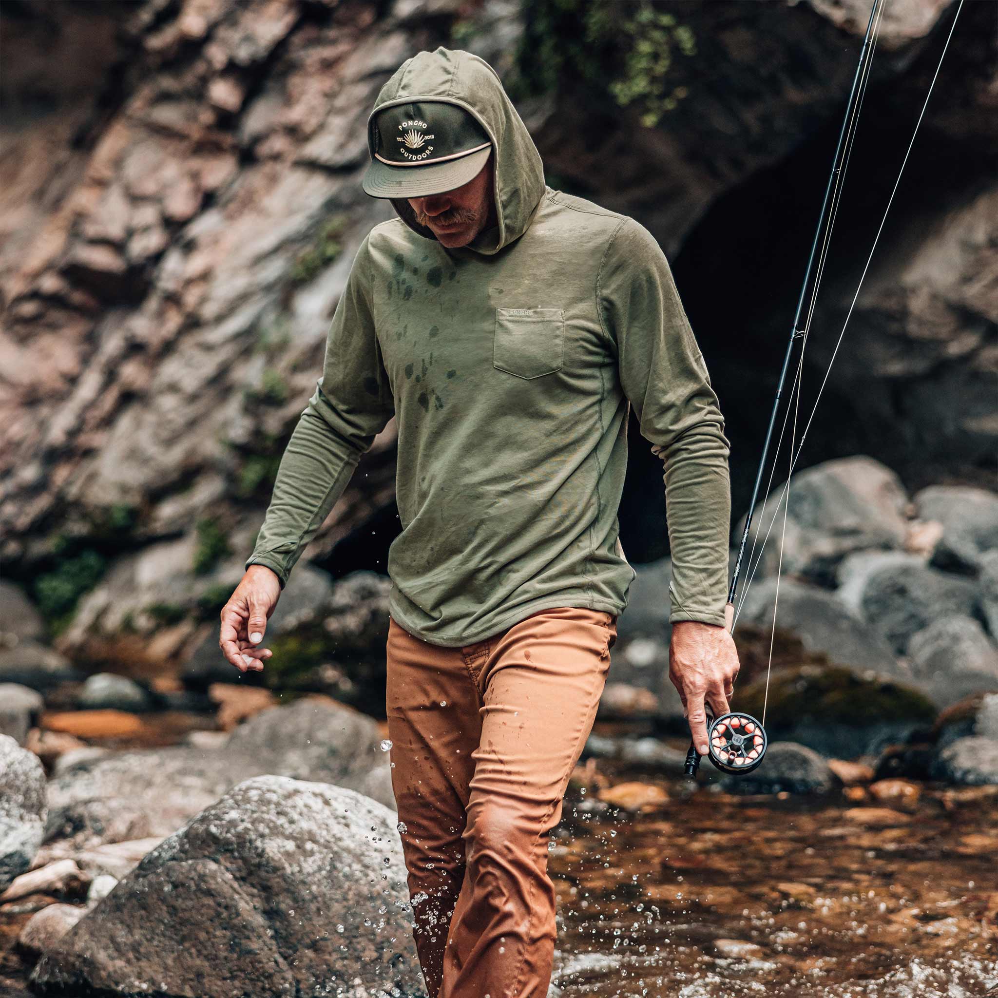 guy walking through water wearing moss green performance hoodie