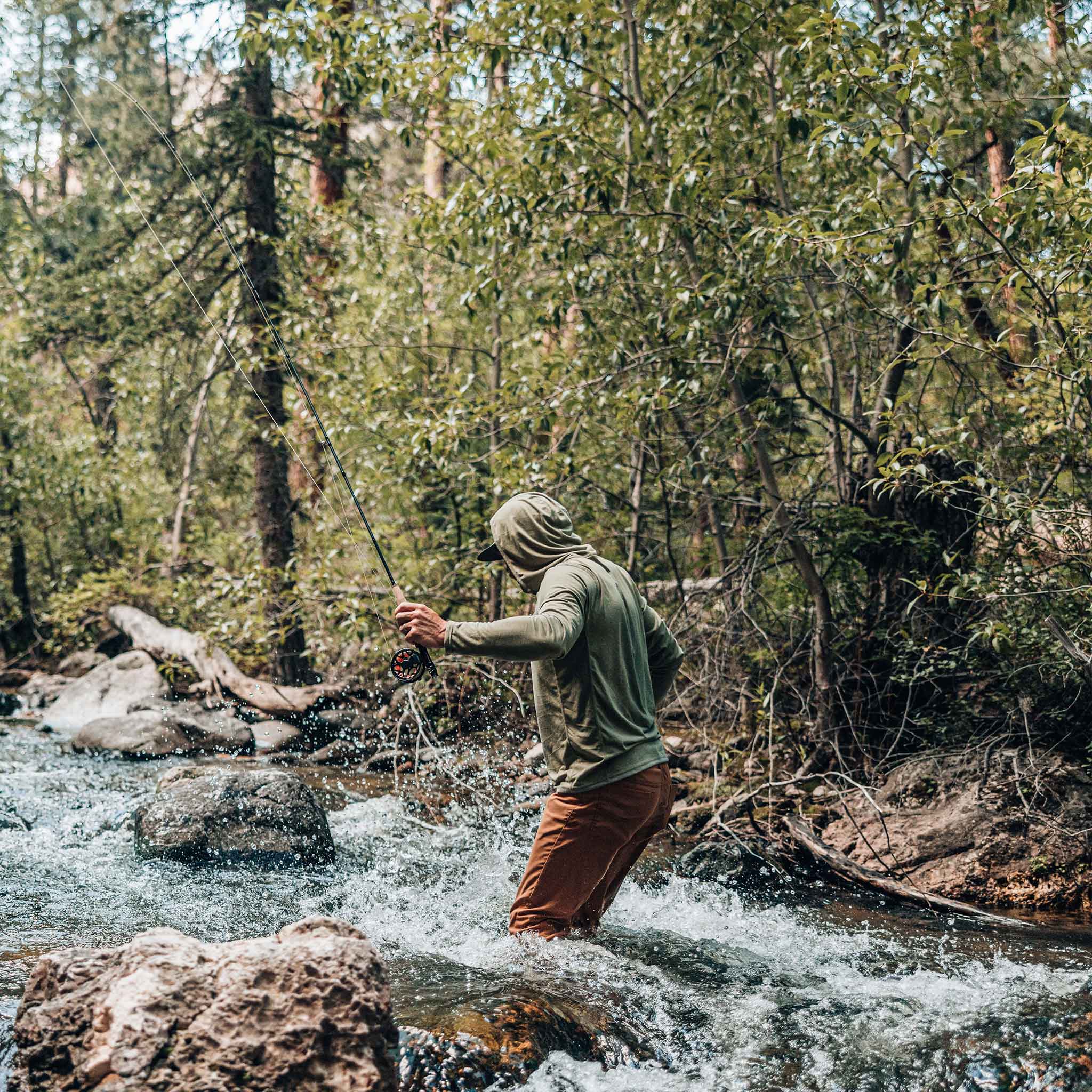 guy walking upstream wearing moss green performance hoodie 