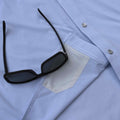 Close up photo of sunglasses on top of the lens cloth on the blue microcheck shirt
