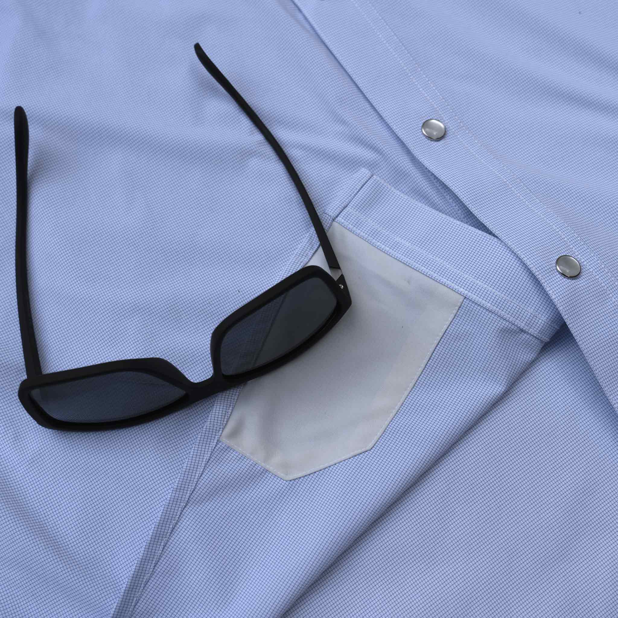 Close up of sunglasses sitting on top of the lens cloth on the blue microcheck western shirt