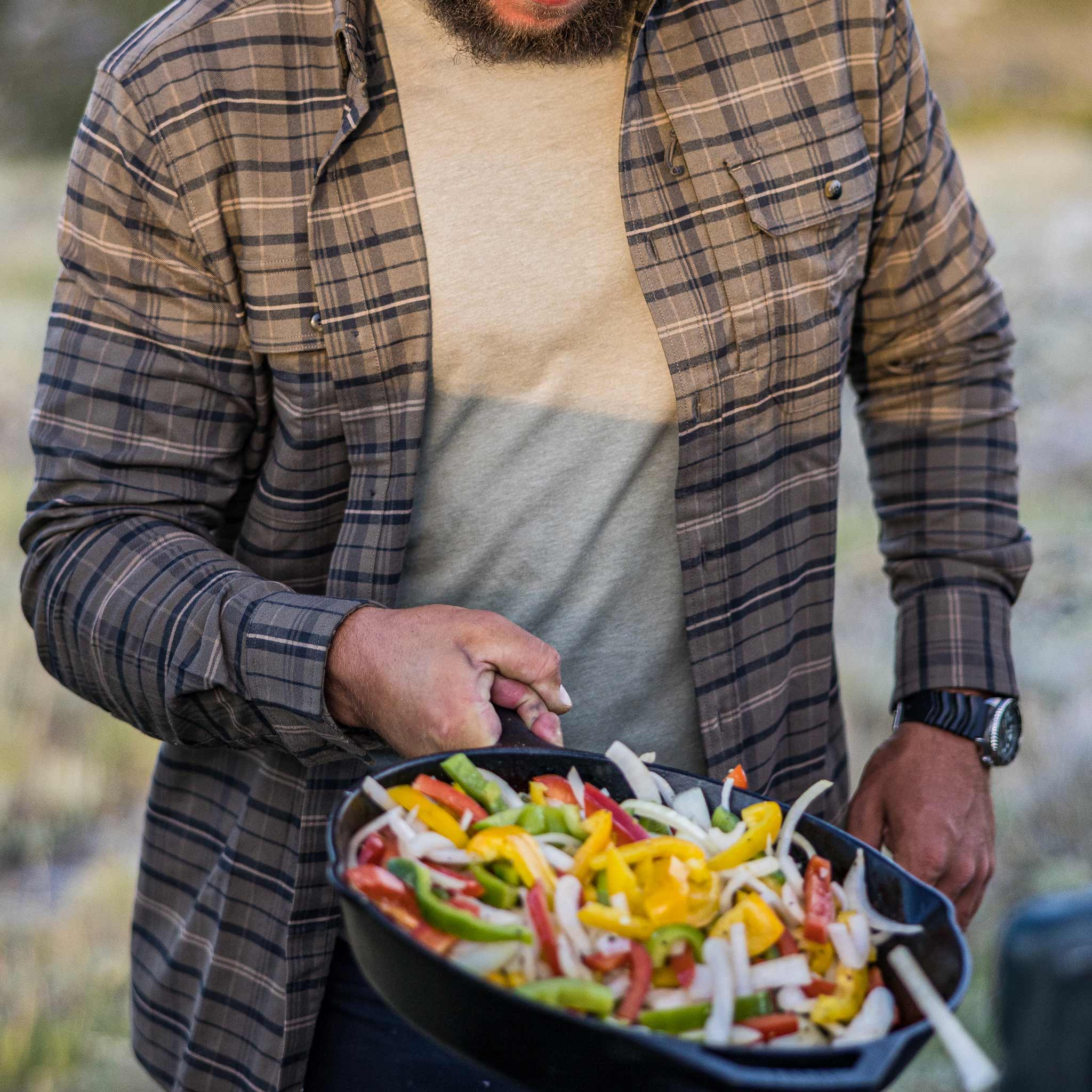 guy wearing shirt cooking veggies in cast iron pan