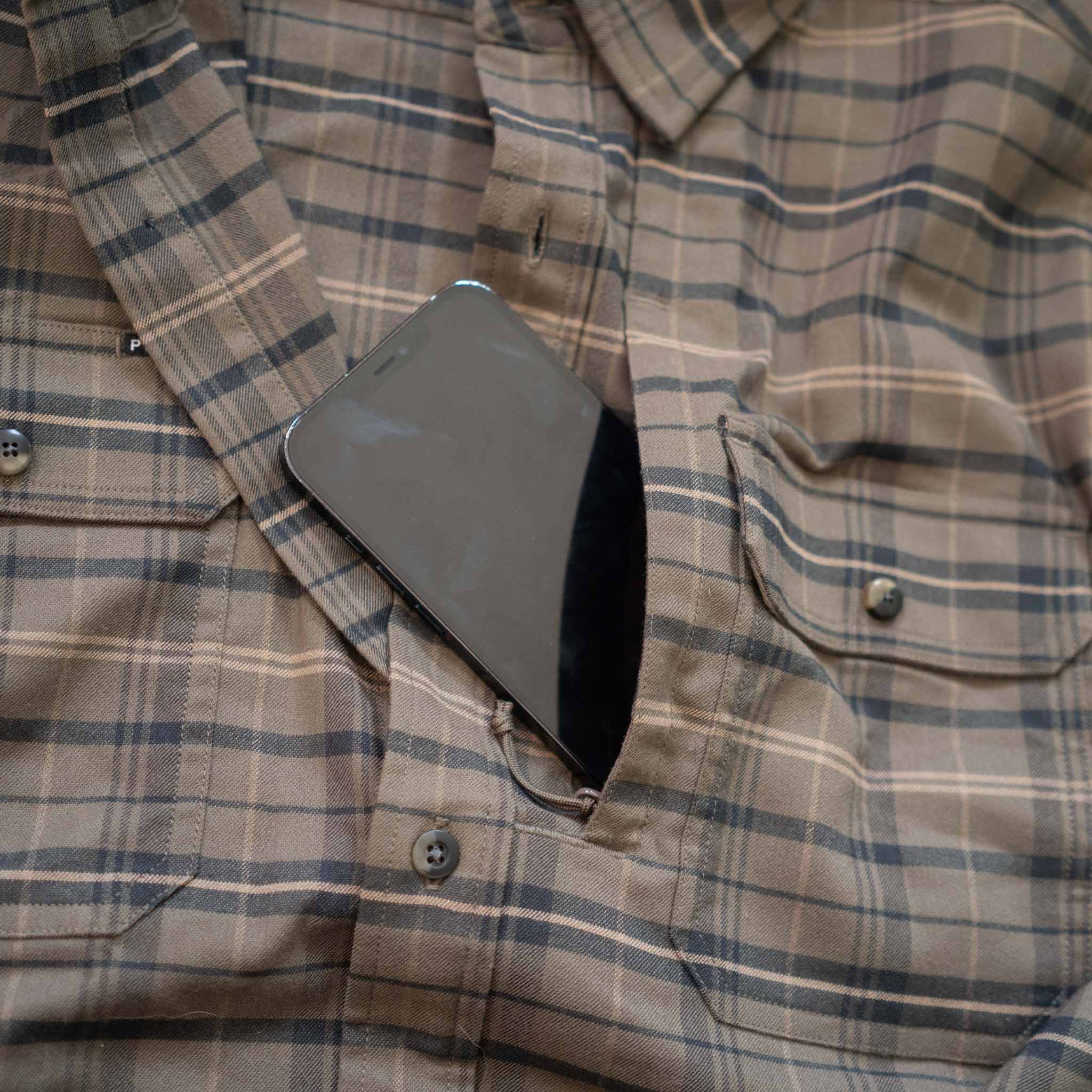 closeup of phone in chest zipper pocket on olive plaid flannel shirt